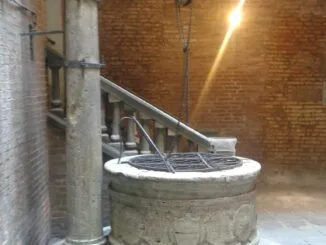 Un puits vieux en pierre dans une cour, touché par un rayon de soleil, métaphore de l'illumination en Franc-maçonnerie.