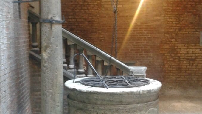 Un puits vieux en pierre dans une cour, touché par un rayon de soleil, métaphore de l'illumination en Franc-maçonnerie.