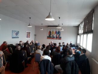 Albert Huguet tenant une conférence devant une assemblée attentive.