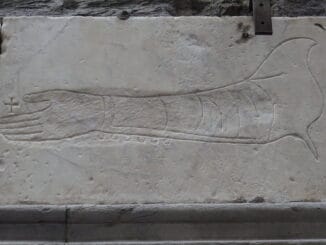 Gravure sur pierre d'un bras et d'une main, évoquant des symboles traditionnels ou historiques.
