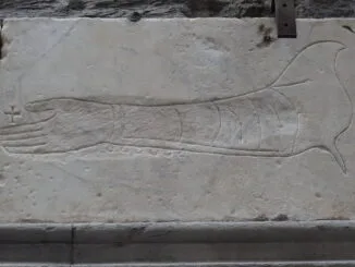 Gravure sur pierre d'un bras et d'une main, évoquant des symboles traditionnels ou historiques.