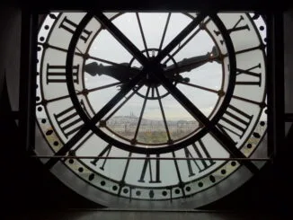 Une horloge avec des chiffres romains, donnant sur une ville.