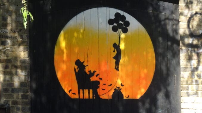 Peinture murale d'une silhouette s'élevant avec des ballons sur fond de coucher de soleil, évoquant l'éveil spirituel en lien avec la franc-maçonnerie.