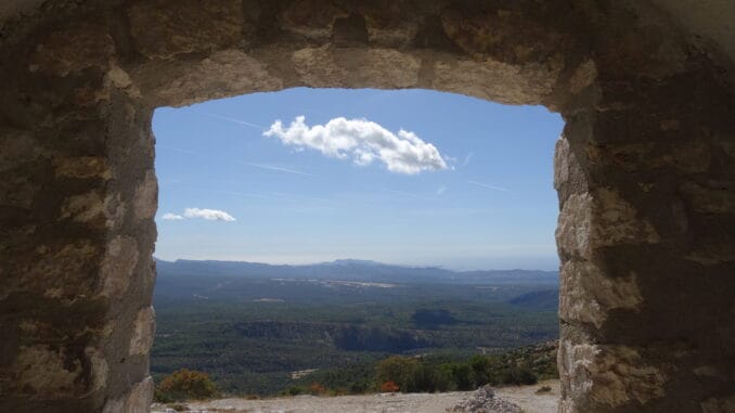 Vision d'Espoir Vue panoramique d'une vallée verdoyante sous un ciel bleu, encadrée par la fenêtre d'une ruine ancienne, métaphore de la recherche de la lumière et de l'espoir.