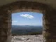 Vue panoramique d'une vallée verdoyante sous un ciel bleu, encadrée par la fenêtre d'une ruine ancienne, métaphore de la recherche de la lumière et de l'espoir.