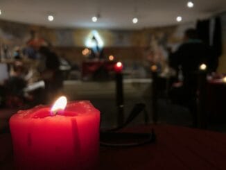 Une bougie rouge illuminant paisiblement une salle aux lumières douces, invitant à la contemplation.