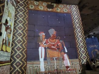 Fresque égyptienne projetée, figures royales et motifs géométriques dans une exposition immersive.